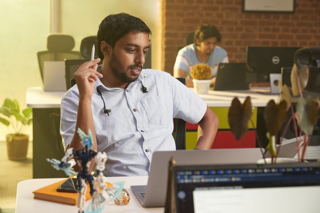 hasaru working in a professional environment holding an apple pencil staring at a screen