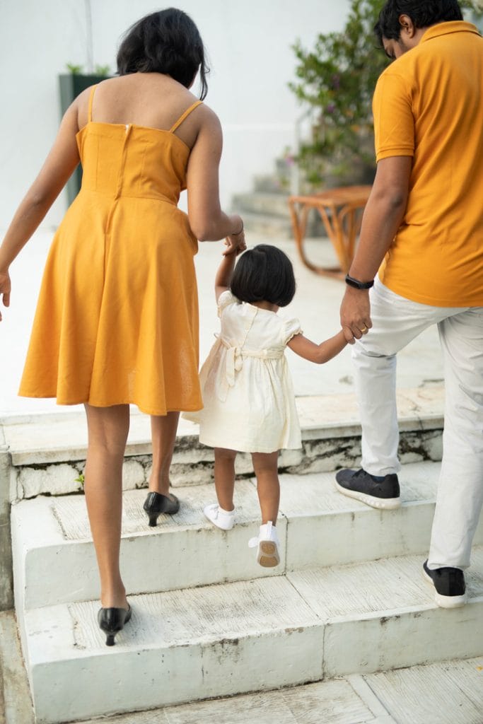 hasaru with his wife and daughter climbing stairs wearing yellow matching clothing