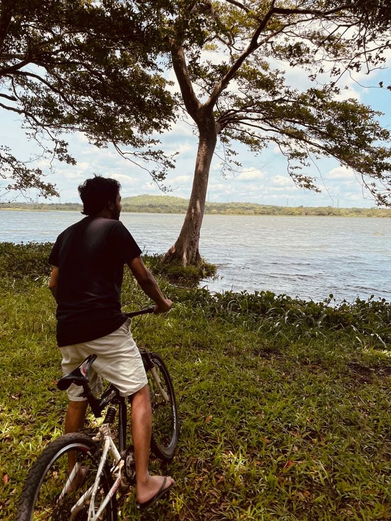 hasaru likes to travel to beautiful destinations, this picture shows hasaru on a bike looking at a beautiful lake